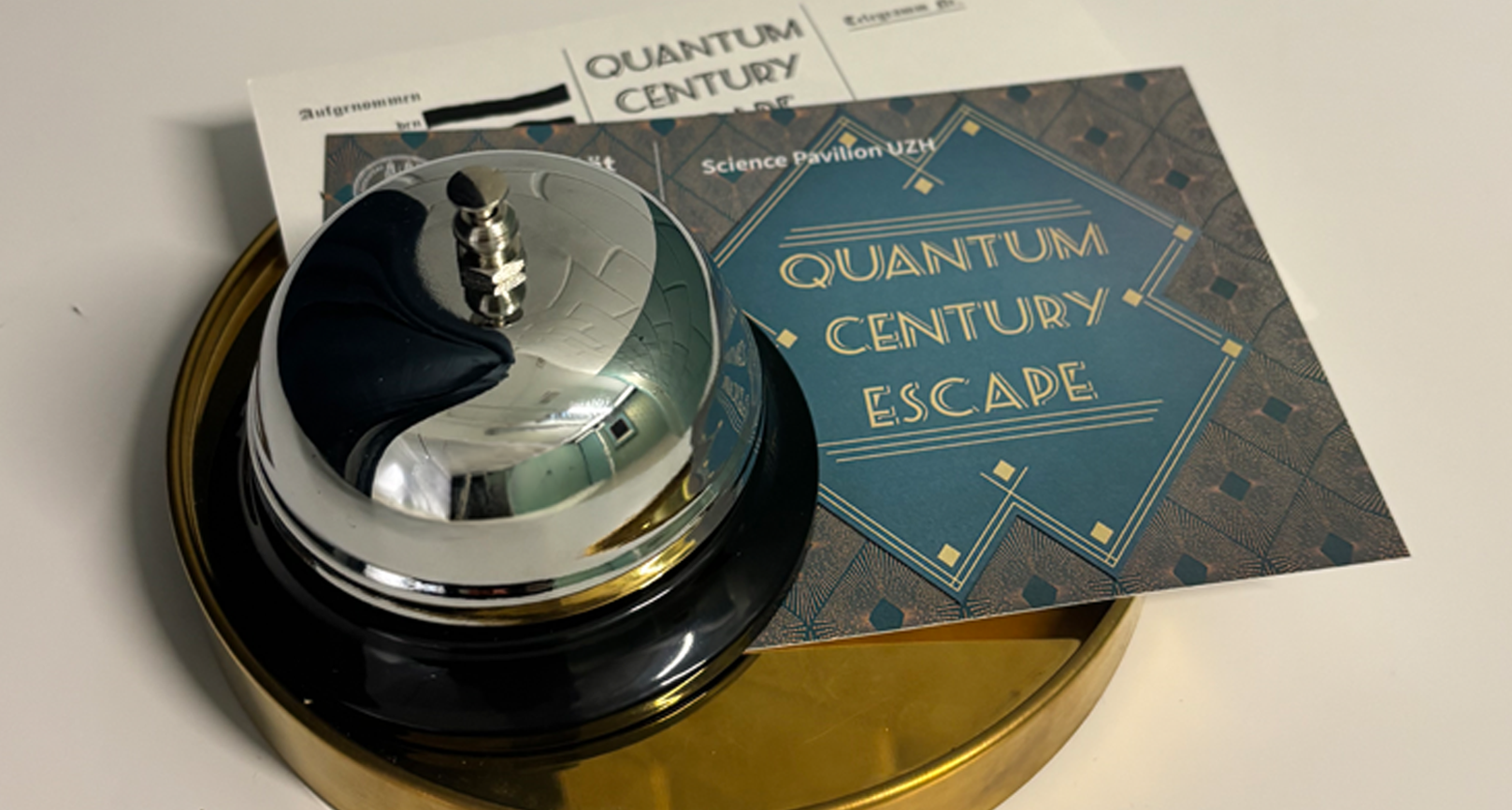 Tischklingel und Quantum Century Escape Room Flyer auf rundem Tablar.