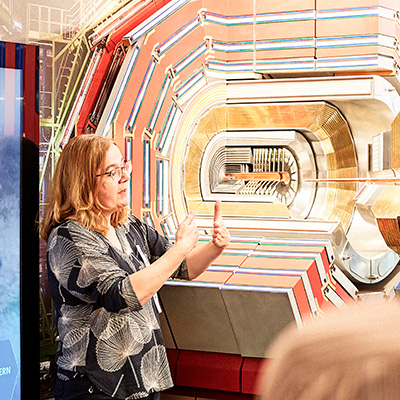Bild zeigt eine Person die, im Rahmen einer Physik Führung im Science Pavilion UZH, das CERN Experiment Modell erklärt.